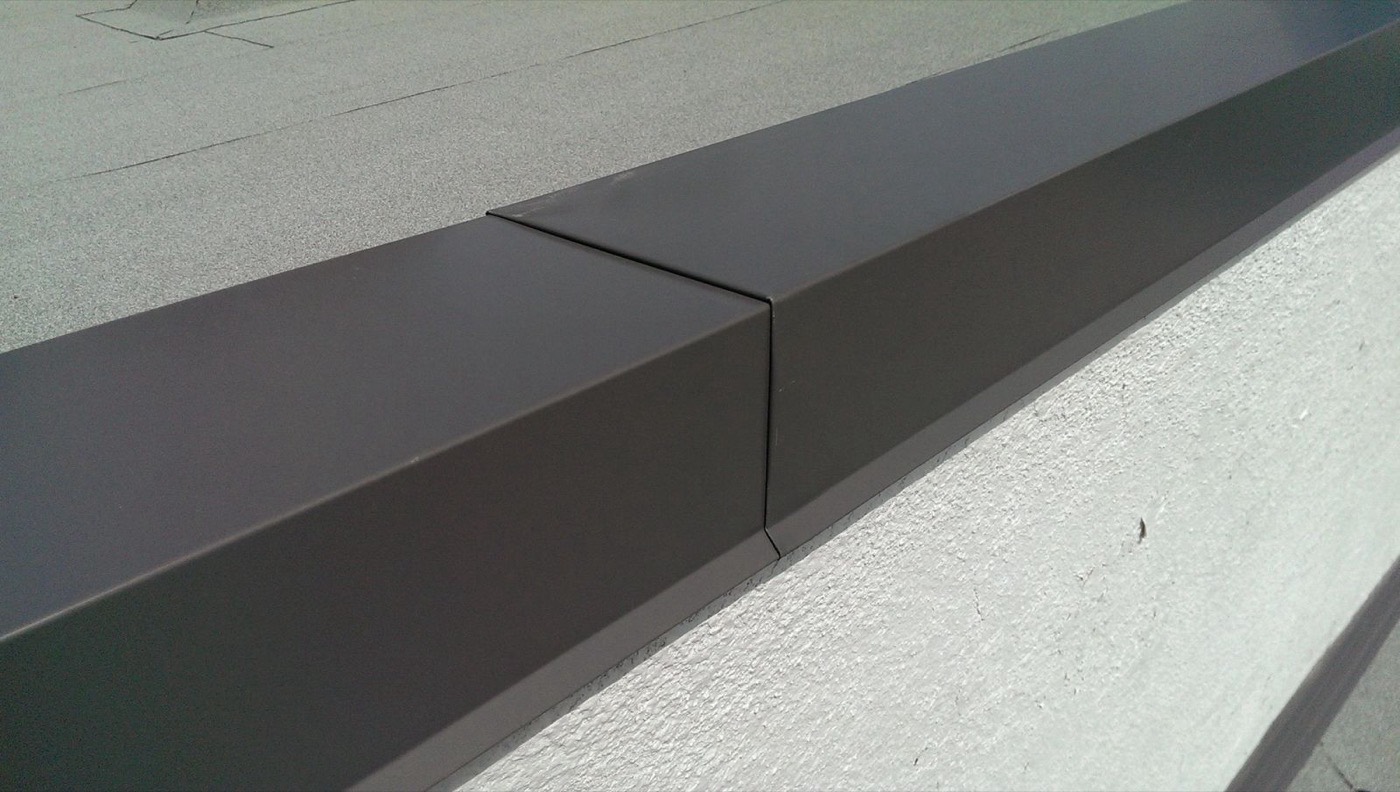 Dark brown metal parapet cap flashing with a crisp locked joint on a flat roof edge